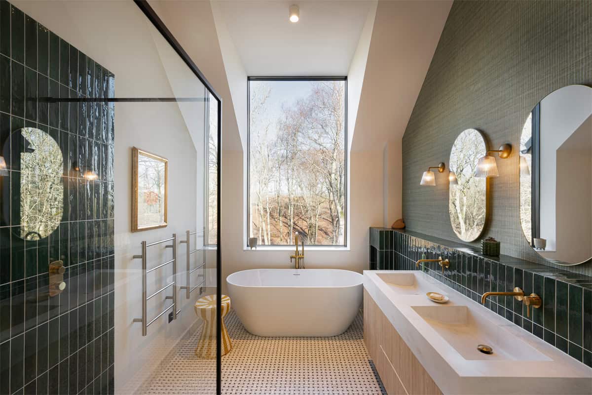 Hazelbridge Cottage bathroom with freestanding bath, green tile, brass fittings, and woodland views